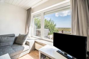 a living room with a tv and a large window at Seehaus Juist in Juist