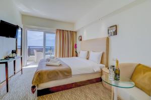 Olympian Bay Grand Resort في ليبتوكاريا: غرفه فندقيه بسرير واريكه