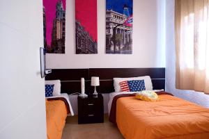 マドリードにあるReina Victoria Apartaments & SuiteS TPHのベッドルーム1室(ベッド2台付)が備わります。壁には絵画が飾られています。