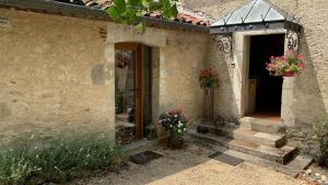 un bâtiment avec deux plantes en pot sur la porte et des escaliers dans l'établissement La Bastide Portoly B&B "Pruneaux", à Penne-dʼAgenais