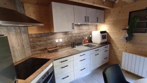 a kitchen with white cabinets and a microwave at Valley Lodge in La Bresse