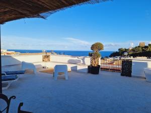 a patio with white chairs and a view of the ocean at Casa Geloso in Ustica