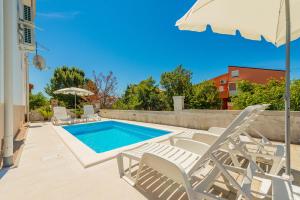 uma piscina com cadeiras e um guarda-sol em La Prima Privlaka Luxury Apartments I em Privlaka