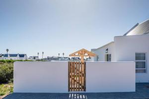 a house with white walls and a wooden gate at Whale & Tortoise - Lampiesbaai in St Helena Bay