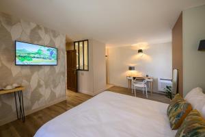 a hotel room with a bed and a tv on a wall at Villa Sainte Anne in Gigondas