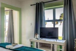 a living room with a television and a window at Whale & Tortoise - Lampiesbaai in St Helena Bay