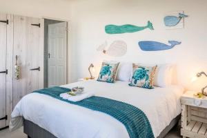 a bedroom with a large white bed with blue pillows at Whale & Tortoise - Lampiesbaai in St Helena Bay