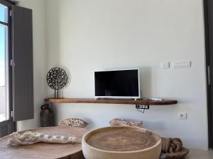 Habitación con TV y mesa con ordenador portátil en un estante. en ZETINE SUITES SIKINOs en Síkinos