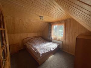 ヤブルニツァにあるMini Cottageの木製の部屋にベッド付きの小さなベッドルーム1室