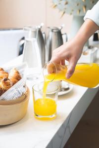 a person pouring orange juice into a glass on a counter at Iberostar Selection Paseo de Gracia 4 Sup in Barcelona