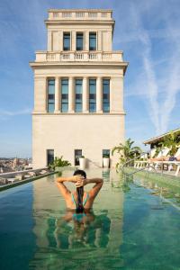 a person sitting in the water in front of a building at Iberostar Selection Paseo de Gracia 4 Sup in Barcelona