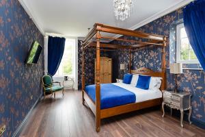 a bedroom with a canopy bed and blue wallpaper at RainHill Hall Hotel in Rainhull