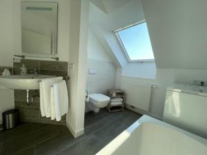 ein Bad mit einem Waschbecken, einem WC und einem Fenster in der Unterkunft Moderne Wohnung mit Balkon inmitten der Lausitz in Bernsdorf