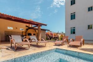 a patio with chairs and a swimming pool next to a building at SAN GIACOMO I Apartamentos por Temporada para amigos, famílias e empresas no Porto das Dunas - Ceará in Aquiraz