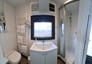 a bathroom with a sink and a shower and a television at Hausboot Lobster Bremerhaven in Bremerhaven