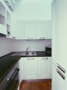 una cocina con armarios blancos y fregadero en San Marco LT, en Porto Rotondo