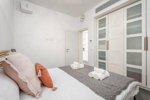 Un dormitorio blanco con una cama con toallas. en Gordon Area - Amazing one BDR close to the beach en Tel Aviv