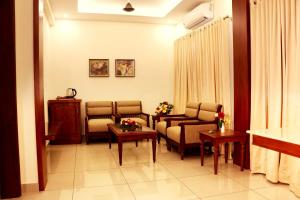 - une salle d'attente avec des chaises et des tables dans l'établissement Bhasuri Inn Guruvayoor, à Guruvāyūr