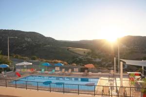 a view of a swimming pool with the sun setting at Panoramic Holidays - Standard 73 in Peyia