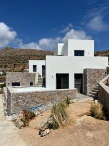 a white house with a stone wall at ZETINE SUITES SIKINOs in Síkinos