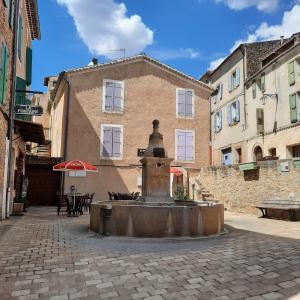une fontaine au milieu d'une rue avec un bâtiment dans l'établissement Campaneta, à Saint-Martin-de-Brômes