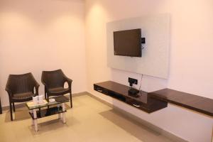 Pokój z 2 krzesłami i telewizorem na ścianie w obiekcie HOTEL ORANGE INN w mieście Patna