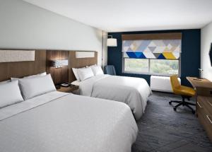 Hawaiian GardensにあるHoliday Inn Express & Suites - Hawaiian Gardens, an IHG Hotelのベッド2台、デスク、窓が備わるホテルルームです。