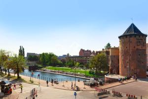 ein Gebäude mit einem Turm neben einem Fluss in der Unterkunft Elite Apartments Waterlane SPA in Danzig