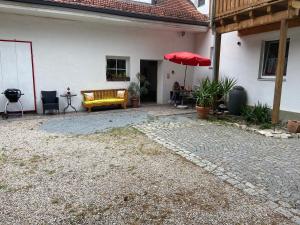 um pátio com um sofá amarelo e um guarda-chuva vermelho em Casa Andrea 3-Zimmer Wohnung em Wallersdorf