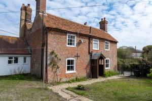 una vecchia casa di mattoni rossi con un garage bianco di Two Sides Cottage a Lymington