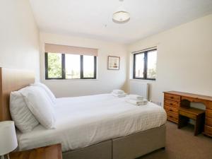 a bedroom with a bed and a desk and windows at Marine Court Two Bedroom Second-floor Apartment 33 in Littlehampton