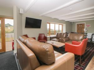 uma sala de estar com mobiliário de couro e uma televisão de ecrã plano em Harcombe House Bungalow 5 em Newton Abbot
