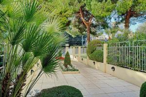 un jardín con una valla y algunas plantas y árboles en HENRI CAMILLE REAL ESTATE - GOLDEN - one bedroom apt swimming pool, en Cannes