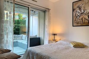 1 dormitorio con 1 cama y puerta corredera de cristal en HENRI CAMILLE REAL ESTATE - GOLDEN - one bedroom apt swimming pool, en Cannes