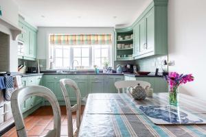 a kitchen with green cabinets and a table with chairs at The Old Post Office in Lymington