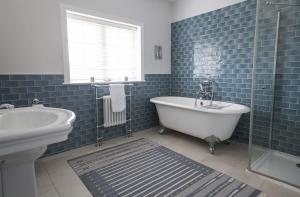a blue tiled bathroom with a tub and a sink at The Old Post Office in Lymington +46 photos