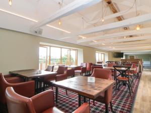 a dining room with tables and chairs and windows at Harcombe House Bungalow 7 in Newton Abbot