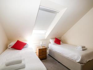 two beds with red pillows in a attic bedroom at Marine Court Three Bedroom Second-floor Apartment 34 in Littlehampton +24 photos
