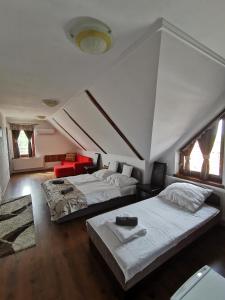 ein Schlafzimmer mit 2 Betten und ein Zimmer mit einem Sofa in der Unterkunft Merlot Borhotel és Látványpince in Edelény
