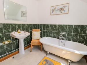 a green tiled bathroom with a tub and a sink at Preswylfa in Conwy