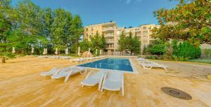 une piscine avec des chaises longues et un bâtiment dans l'établissement Kamenec Hotel, à Nessebar