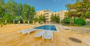 a swimming pool with lounge chairs and a building at Kamenec Hotel in Nesebar