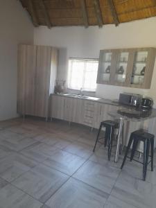 a kitchen with wooden cabinets and stools in a room at Banabaka spa and venue in White River