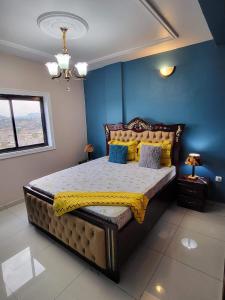 a bedroom with a large bed with yellow sheets and blue walls at Lux Résidence in Yaoundé