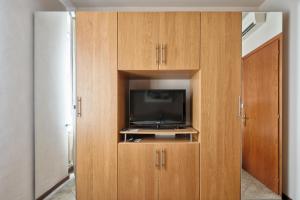 トリノにあるMoleloca - San Tommaso Apartmentのテレビ付きの木製キャビネットが備わる客室です。