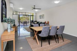 comedor y sala de estar con mesa y sillas en Pool View City Centre Apartment 202 en Cairns