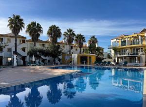 a swimming pool with palm trees and buildings at Grupo Morgado - Quinta do Morgado - Morgado Exclusive in Tavira
