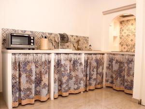 una cucina con bancone, tende e forno a microonde di Casa Vacanze L'essenziale a Martina Franca