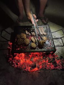 una persona sta cucinando cibo su una griglia di Muweti Bush Lodge a Grietjie Game Reserve
