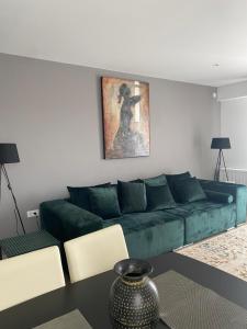 ein Wohnzimmer mit einem grünen Sofa und einem Tisch in der Unterkunft Bucharest Airport Suites & Villas in Otopeni